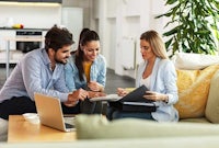 a group of people sitting on a couch looking at a laptop